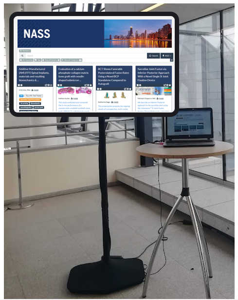 Image showing a large screen on which you can see the NASS ePoster showcase. Next to the screen is a laptop computer on a table.